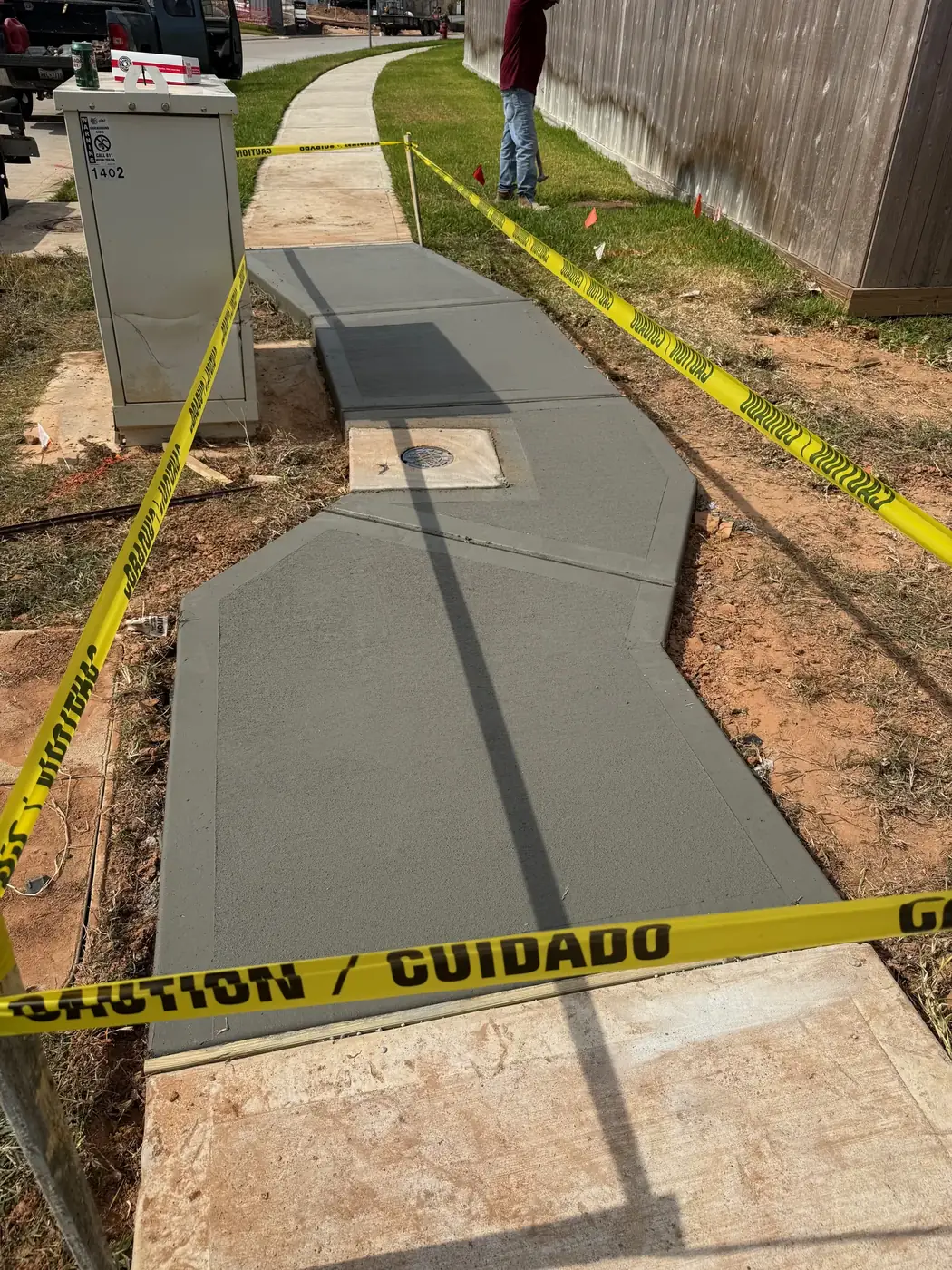 New concrete sidewalk replacement with caution tape around the work area